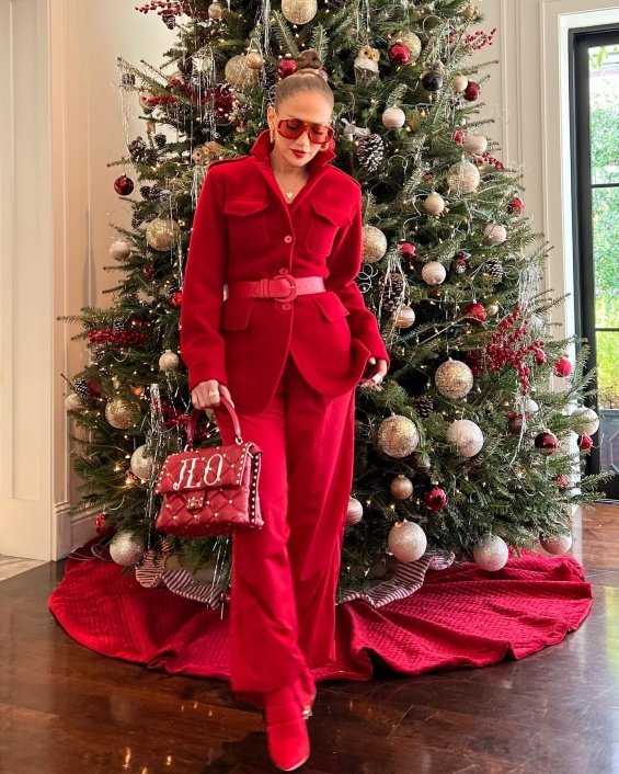 Jennifer Lopez in red next to a Christmas tree