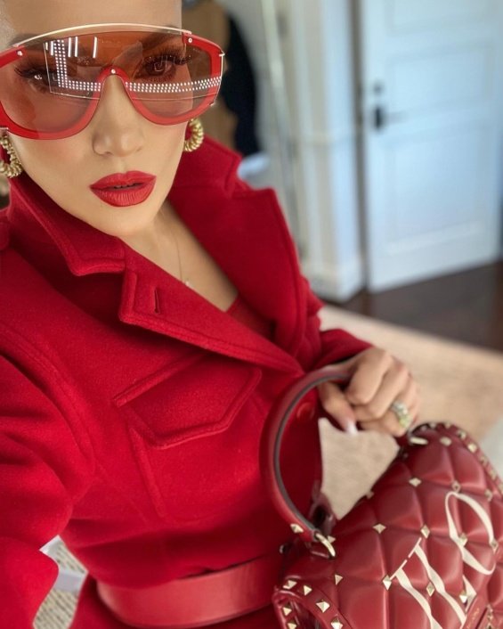 Jennifer Lopez in red next to a Christmas tree