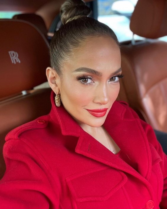 Jennifer Lopez in red next to a Christmas tree